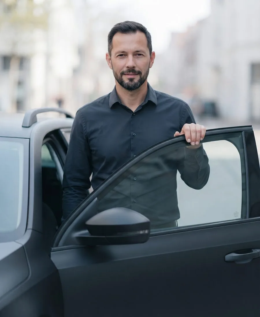 Fahrer steht neben der ge&ouml;ffneten Fahrert&uuml;r