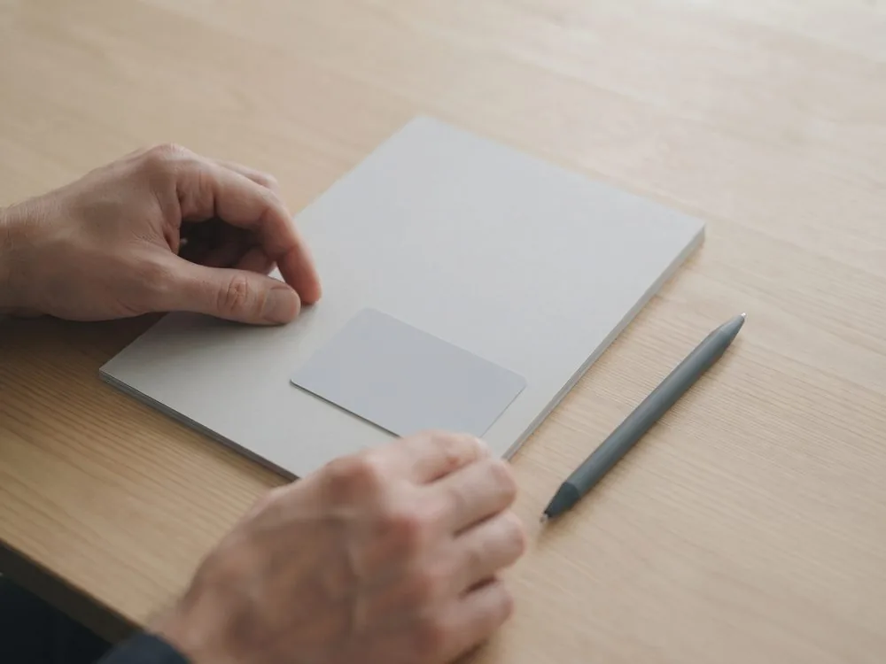 Zwei H&auml;nde legen einen Papierstapel und eine leere Karte auf einen Tisch